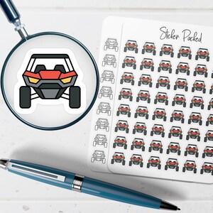 May include: A sticker sheet labeled Sticker Packed featuring multiple small illustrations of a red and black off-road vehicle. A magnifying glass shows a larger version of the vehicle sticker, and a blue pen lies horizontally across the bottom.