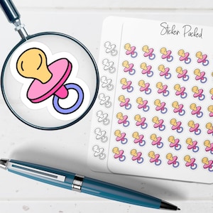 May include: A magnifying glass focuses on a sticker of a baby pacifier with a yellow nipple, pink shield, and blue ring. A sheet of stickers with multiple pacifier designs is visible. A blue pen is in the foreground. The sheet is labeled "Sticker Packed."