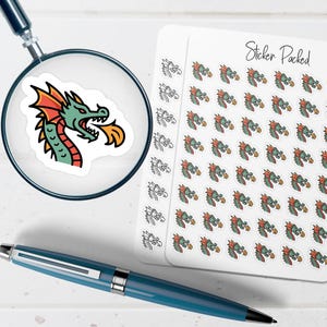 May include: A sheet of small stickers featuring a green dragon head breathing orange fire, with the text Sticker Packed at the top. A magnifying glass shows one dragon sticker in detail, and a blue pen lies horizontally across the bottom.