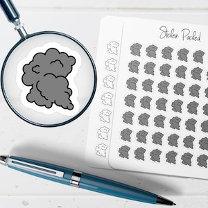 May include: A sticker sheet labeled Sticker Packed featuring multiple small gray cloud stickers and outline-only cloud stickers. A magnifying glass focuses on one gray cloud sticker, and a blue pen lies horizontally below the sticker sheet.