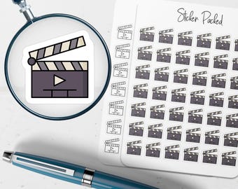 May include: A sheet of stickers featuring a film clapperboard design, with a magnifying glass and a pen in the foreground. The clapperboard stickers are in a repeating pattern. The text "Sticker Packed" is visible.