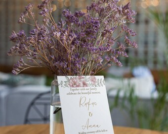 Könnte beinhalten: Eine Hochzeitseinladung mit floralen Akzenten und den Namen Rufus & Anna. Die Einladung befindet sich vor einer Glasvase mit lila Blumen. Die Worte "Digital Download" stehen unten.