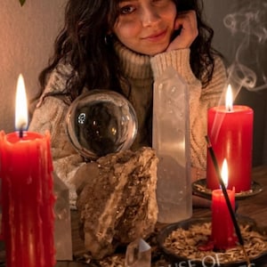 May include: A collection of items including three red pillar candles, a clear glass crystal ball, a tall clear quartz point, a raw mineral cluster, and a burning incense stick. The text House of Magic Miracles is printed at the bottom.