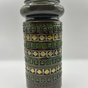 May include: A green and brown ceramic vase with a geometric pattern. The vase has a wide mouth and a narrow base.