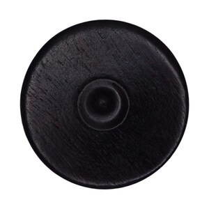 May include: A black wooden coaster with a round shape and a small circular indentation in the center.