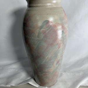 May include: A tall ceramic vase with a flared rim and a smooth, tapered body. The surface features a mottled, blended glaze with soft washes of dusty rose, muted sage green, and light gray, creating a painterly effect across the entire exterior.