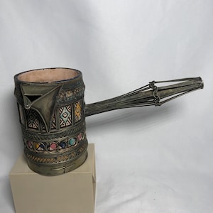 May include: A set of three ceramic mugs with a speckled, matte finish. The mugs are in shades of cream, light gray, and dark gray. Each mug has a simple, minimalist design and a rounded handle.