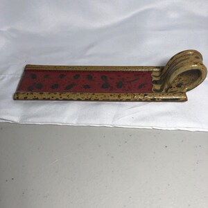 May include: A rectangular ceramic tray with a flat base and a curved, loop-shaped handle on one end. The tray features a deep red center with dark brown speckles, bordered by a speckled tan and brown rim that extends to the handle.