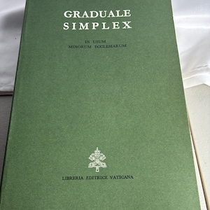 May include: A green hardcover book titled Graduale Simplex In Usum Minorum Ecclesiarum with white text on the front cover. The cover features a small white emblem above the text Libreria Editrice Vaticana at the bottom center of the book.