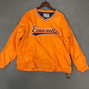 May include: Bright orange pullover jacket with a V-neck collar and long sleeves. The word "Evansville" is embroidered across the chest in a script font with a blue outline. The jacket has a drawstring at the bottom hem.