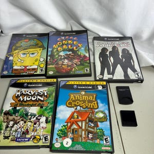 May include: A collection of five Nintendo GameCube video games including SpongeBob SquarePants, Super Monkey Ball, Charlie's Angels, Harvest Moon: A Wonderful Life, and Animal Crossing, accompanied by two black memory cards for the console.