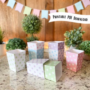 May include: Printable PDF download for six pastel polka dot favor boxes. The boxes are in shades of pink, purple, green, and blue.  The boxes are perfect for party favors or small gifts.