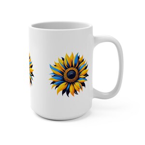 May include: White ceramic mug with a blue and yellow sunflower design. The sunflower has a dark blue center and yellow petals with blue accents.