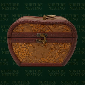 May include: An oval wooden chest with a floral design. The chest has a dark brown frame and a gold floral pattern on the front. It features a brass clasp and hinges, and is suitable for storing small items.
