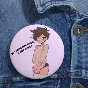 May include: A pink button with a cartoon illustration of a person wearing a pink apron and white thigh-high socks. The text on the button reads "Did someone order a boy wife?"