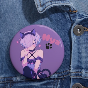May include: Purple button with a cartoon illustration of a person with purple hair wearing a black cat ear headband and a black and white lace dress. The person is holding their hand to their face and has a pink heart next to their cheek. The text "Nyaa" is written in pink on the button.
