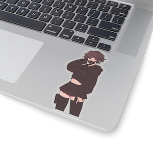 May include: A sticker featuring an anime-style character in a black outfit, including a cropped hoodie, skirt, and knee-high socks. The character has short brown hair, a face mask, and a tactical vest. The sticker is placed on a laptop.