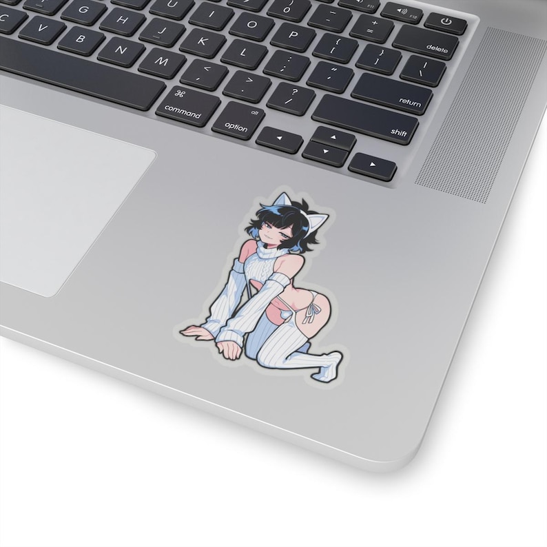 May include: A sticker depicting a cartoon character with black hair, cat ears, and a white and blue outfit. The character is kneeling on a laptop, with the keyboard in the background.