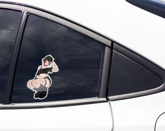 Może przedstawiać: Naklejka winylowa umieszczona na szybie samochodu, przedstawiająca postać w stylu anime z krótkimi ciemnymi włosami i różowymi pasemkami, ubraną w czarny krótki top, czarne szorty, kabaretki i buty na platformie, wykonującą gest pokoju.