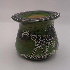 May include: A green stone vase with a white giraffe design. The vase has a wide rim and a rounded body.