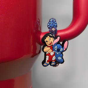 May include: A blue and red character charm featuring Lilo and Stitch from the Disney movie Lilo & Stitch. The charm is attached to a blue beaded bracelet.
