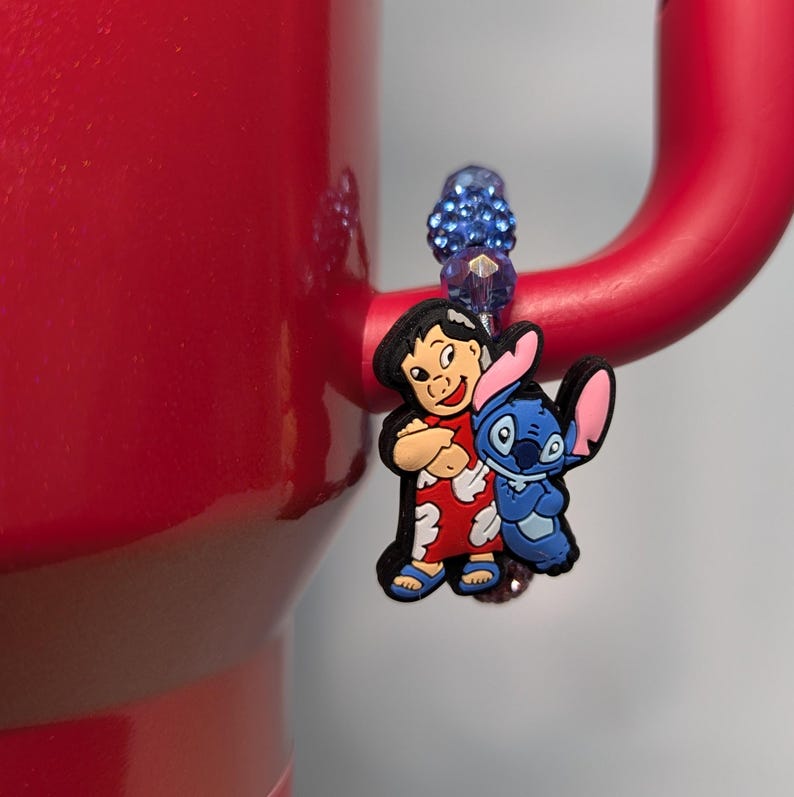 May include: A blue and red character charm featuring Lilo and Stitch from the Disney movie Lilo & Stitch. The charm is attached to a blue beaded bracelet.