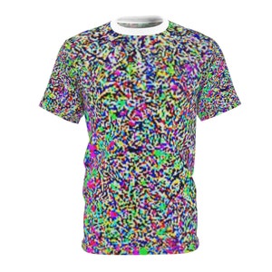 Op de afbeelding: Een t-shirt met korte mouwen met een levendig, gepixeld patroon in een veelvoud aan kleuren, waaronder blauw, groen, roze en geel. De shirt heeft een witte ronde hals. Het algehele ontwerp geeft een digitale of glitch art esthetiek.