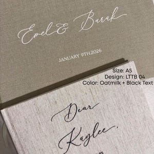K&ouml;nnte beinhalten: Zwei personalisierte B&uuml;cher mit Leinenstruktur. Das obere Buch ist lattefarben mit cremefarbenem Text "Evel & Buck" und "JANUARY 9TH.2026". Das untere Buch ist hafermilchfarben mit schwarzem Text "Dear Kaylee" und "12.20.25".