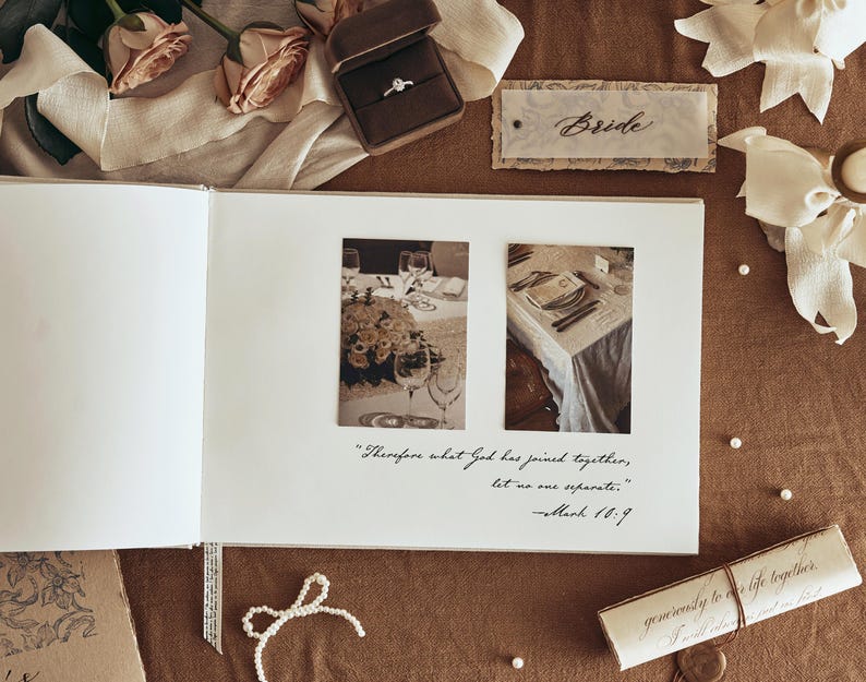 K&ouml;nnte beinhalten: Ein offenes Hochzeitsfotoalbum mit zwei gerahmten Bildern einer Hochzeitstafel. Ein Diamantring in einer braunen Samtbox, ein Etikett mit der Aufschrift "Bride" und eine Schriftrolle sind ebenfalls zu sehen. Das Album enth&auml;lt das Zitat "Was Gott zusammengef&uuml;gt hat, soll der Mensch nicht trennen."