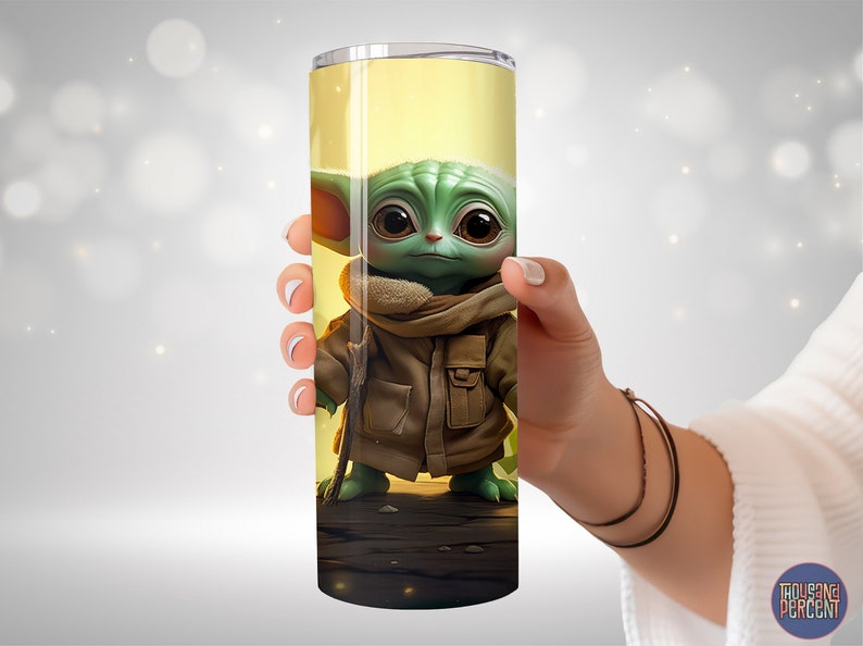 May include: A stainless steel tumbler with a green and brown image of a character from the Star Wars franchise. The character is wearing a brown coat and has large ears.