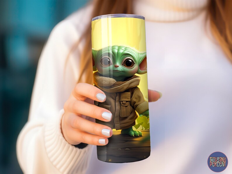May include: A yellow and green stainless steel tumbler with a cartoon image of a green alien character wearing a brown jacket. The alien is standing on a wooden surface.