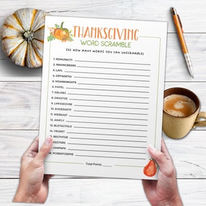 May include: A Thanksgiving-themed word scramble game sheet with the title "Thanksgiving Word Scramble" in orange and green. The sheet is held by hands and includes a pumpkin and a cup of coffee.