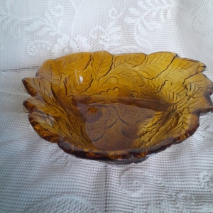 May include: Amber glass bowl with a leaf design. The bowl is shallow and has a wide rim.