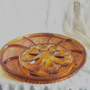 May include: Amber-colored glass serving platter with a central section for dips and surrounding compartments. The platter features a leaf design and a beaded edge, perfect for serving appetizers or snacks.