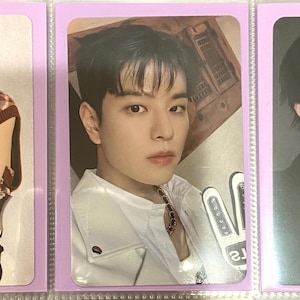 Pode incluir: Três cartões de fotos em mangas protetoras. Os cartões apresentam retratos de jovens. O primeiro cartão mostra uma pessoa em uma blusa estampada. O segundo cartão mostra uma pessoa em uma jaqueta branca. O terceiro cartão mostra uma pessoa em um terno preto.