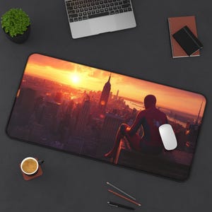 May include: A red and blue superhero figure sits on a rooftop overlooking a city skyline at sunset. The city is filled with skyscrapers and the sun is setting behind them. The figure is wearing a red and blue suit with a spider logo on the chest.