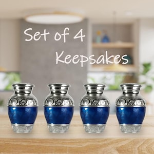 May include: Set of 4 keepsakes. Four small, blue and silver urns with ornate detailing. The urns have a metallic silver top and base, with a vibrant blue center. The text "Set of 4 Keepsakes" is displayed above the urns.