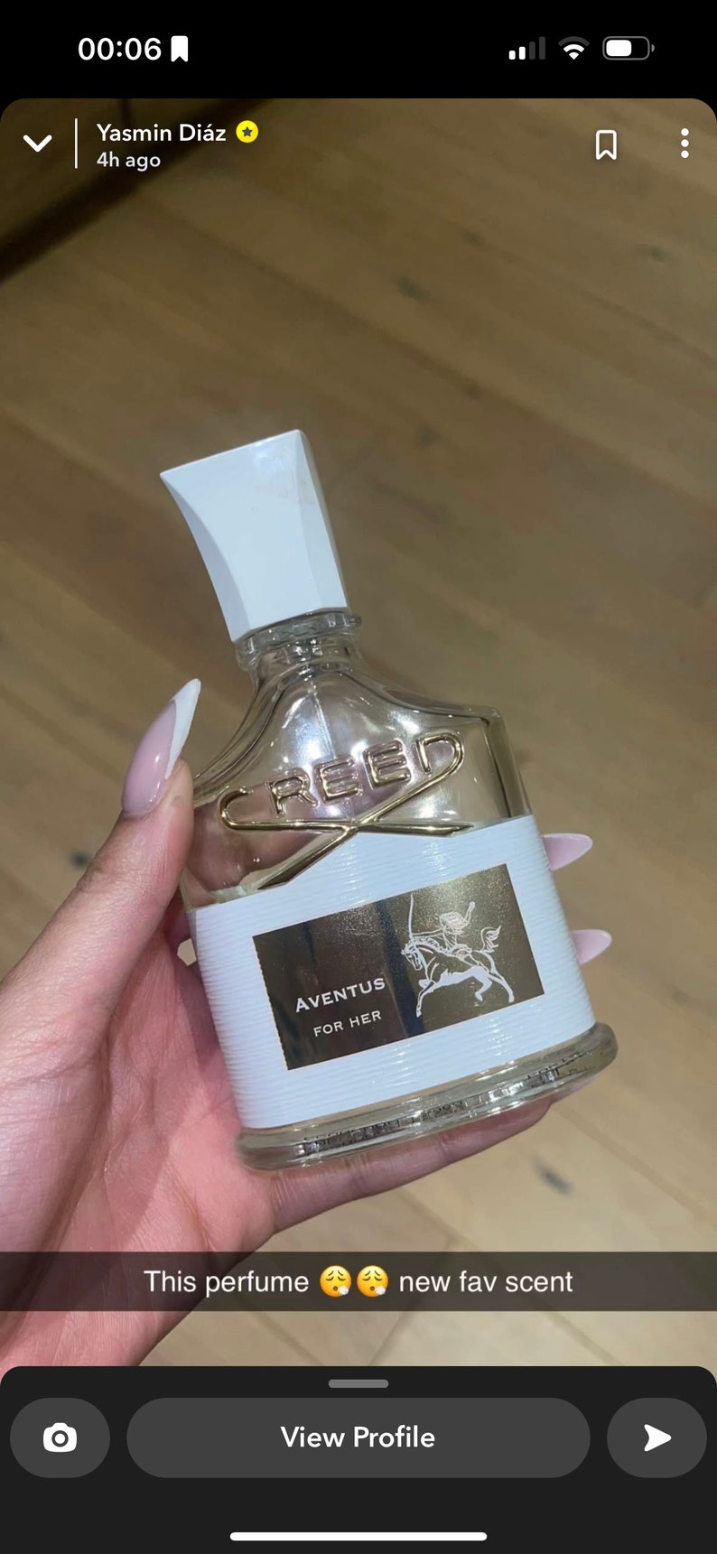 K&ouml;nnte beinhalten: Eine durchsichtige Glasflasche mit Parfum und einem wei&szlig;en Verschluss. Die Flasche hat ein goldenes Etikett mit dem Text "CREED" und "AVENTUS FOR HER".