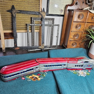 May include: A vintage tin toy train in red and silver featuring the Union Pacific branding. The locomotive and passenger cars display the text Union Pacific and Los Angeles along the sides, with a streamlined design and visible metal rivets.