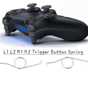 Op de afbeelding: Zwarte gamecontroller met blauwe accenten en twee grijze joysticks. Daaronder worden twee zilveren L1 L2 R1 R2 triggerknopveren weergegeven. De tekst "L1 L2 R1 R2 Trigger Button Spring" is ook zichtbaar.