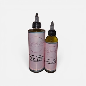 May include: Two brown bottles of hair and scalp serum. The bottles have black caps and pink labels with the text "Mystical Allure Beauty Care" and "Tea Tree Hair & Scalp Serum". The serum inside the bottles is a yellow-green colour.