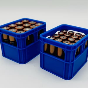 Könnte beinhalten: Zwei blaue Kunststoffkisten gefüllt mit AA-Batterien. Die Batterien sind ordentlich in den Kisten angeordnet, wobei die Pluspole sichtbar sind. Die Kisten sind leuchtend blau und stehen vor einem schlichten weißen Hintergrund.
