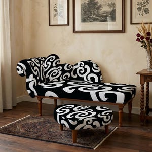 Op de afbeelding: Een chaise longue en bijpassende voetenbank met een opvallend zwart-wit wervelpatroon. Het meubilair heeft houten poten en de chaise longue heeft een gebogen rugleuning. De bekleding toont een doorlopend grafisch ontwerp van witte spiralen op zwart.