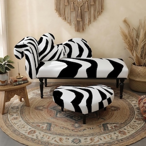 May include: A chaise lounge and a matching heart-shaped ottoman, both upholstered in a bold black and white zebra-striped fabric. The chaise features a curved backrest and dark wooden legs, while the ottoman stands on short black legs.