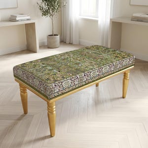 Peut inclure: Un banc rectangulaire doté d'une assise rembourrée recouverte d'un tissu vert orné d'un motif floral et botanique multicolore détaillé. Le banc repose sur quatre pieds dorés, lisses et fuselés, au design arrondi et tourné.