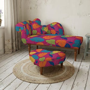 Puede incluir: Una chaise longue y un otomano a juego en forma de corazón con un fondo magenta vibrante y un patrón repetitivo de hojas estilizadas en tonos naranja, amarillo, verde lima y azul turquesa, sobre cuatro patas de madera torneada.