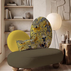 May include: A low-profile sofa with a dark olive green seat and four rounded wooden feet. It features two circular backrests: one solid yellow and one patterned with a yellow, blue, and black historical hunting scene, plus a matching rectangular pillow.