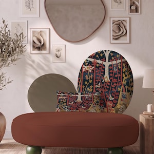 May include: A low-profile, terracotta-coloured bench with four dark green spherical feet. It features a rectangular throw pillow with a dark blue, red, and yellow forest-themed tapestry pattern, placed against a large, circular matching wall art piece.