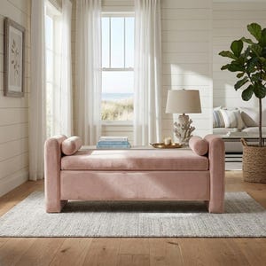 Pode incluir: Um banco de armazenamento retangular estofado em tecido de veludo rosa claro macio. O banco apresenta duas almofadas cilíndricas em cada extremidade, um assento almofadado plano e uma base sólida, proporcionando uma aparência limpa e estruturada.