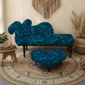 Può includere: Una chaise longue e un pouf a forma di cuore abbinato, entrambi rivestiti in un tessuto blu profondo con un motivo a vortice che ricorda le onde. La chaise longue presenta uno schienale alto e curvo e gambe in legno scuro, mentre il pouf ha gambe corte.